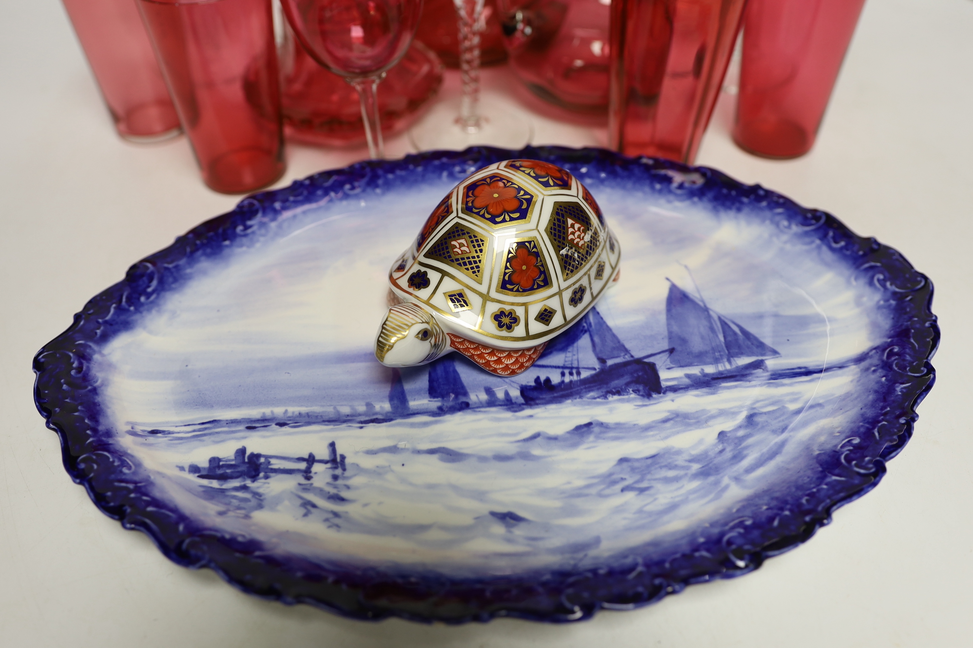 A Royal Crown Derby oval wall plate, a tortoise figure model and thirteen cranberry glass items including wine glasses, a decanter, etc. (15)